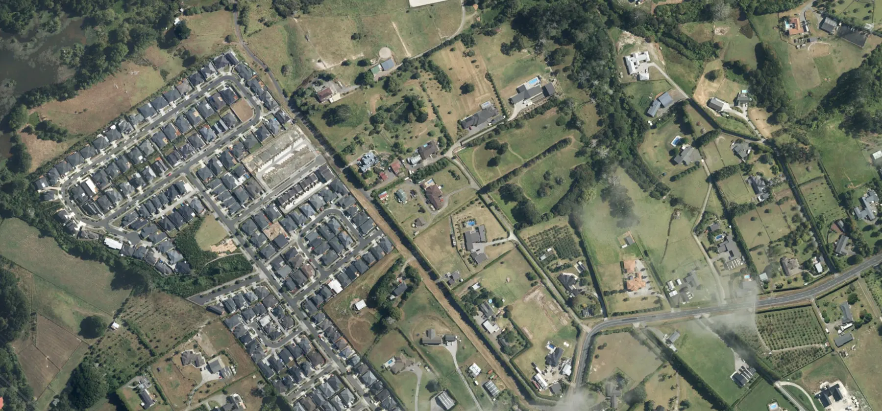 Wider aerial context around Oraha Road, Kumeū. Includes neighbouring properties; site boundaries are not shown.